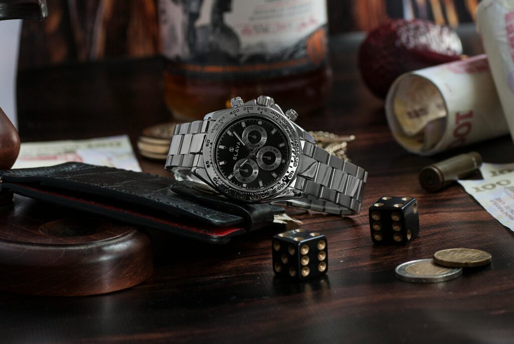 Elegant wristwatch among dice, coins, and banknotes, highlighting luxury and gambling themes.